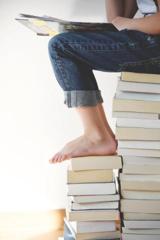 Woman reading, sitting on a pile of books